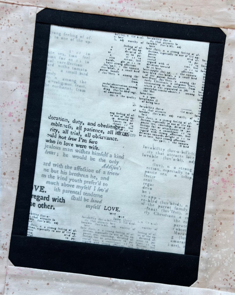 A non branded tablet is depicted in fabric, with fabric that has multiple lines of text used for the center screen portion. Peach and gold flecked fabric frames the block.